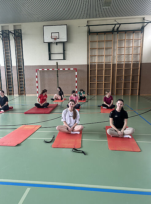 Schülerinnen sitzen auf Yogamatten