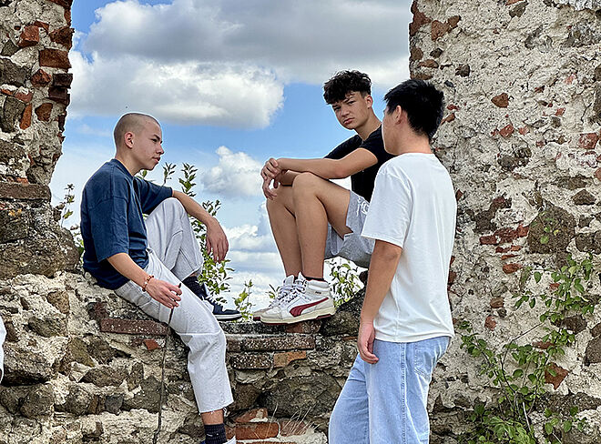 Drei Schüler sitzen auf Burgmauer