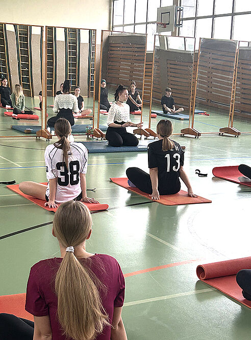 Schülerinnen sitzen auf Yogamatten