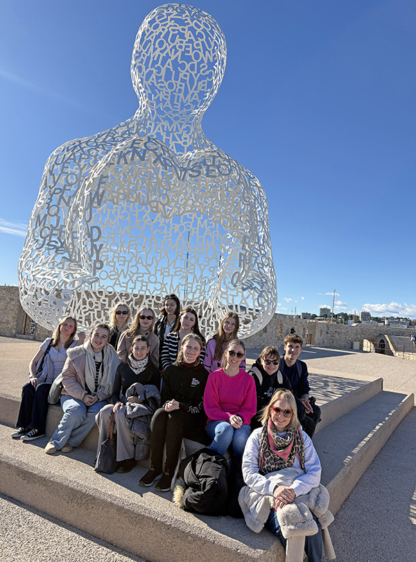 Gruppenfoto vor menschlicher Statue bei Sonnenschein