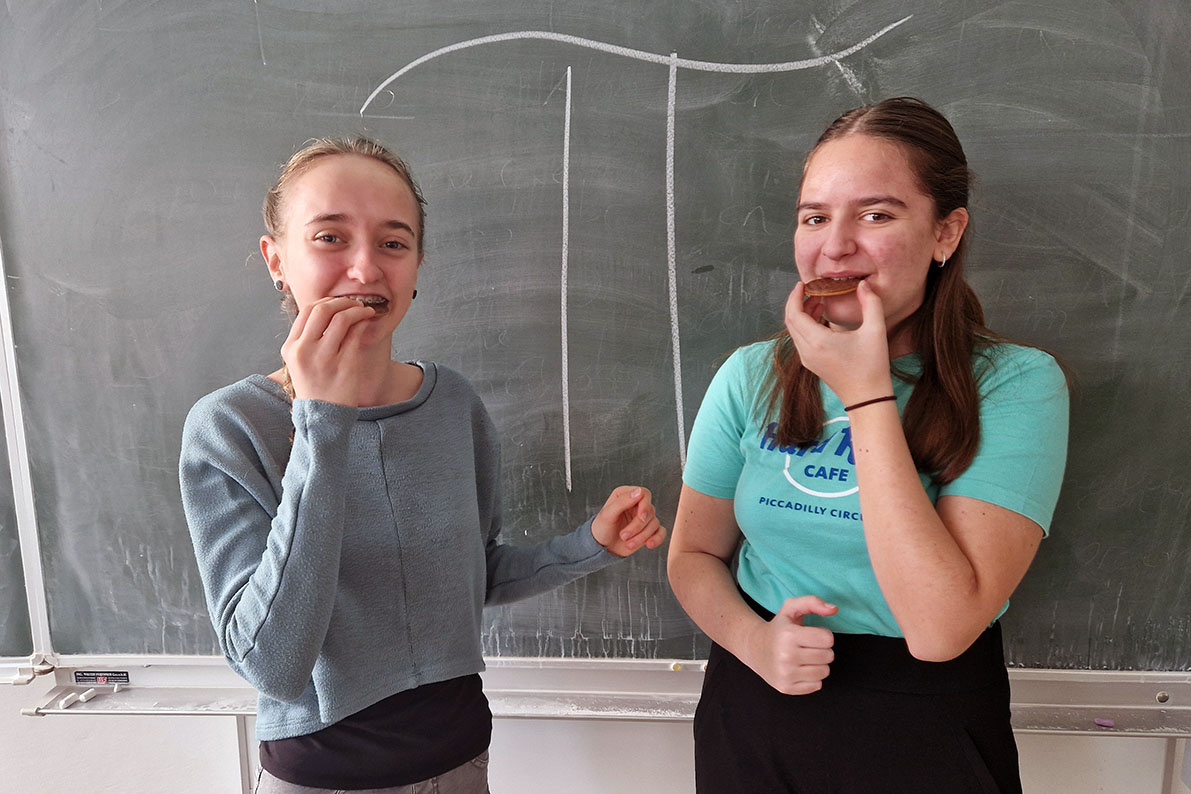 2 Schülerinnen mit Keksen im Mund