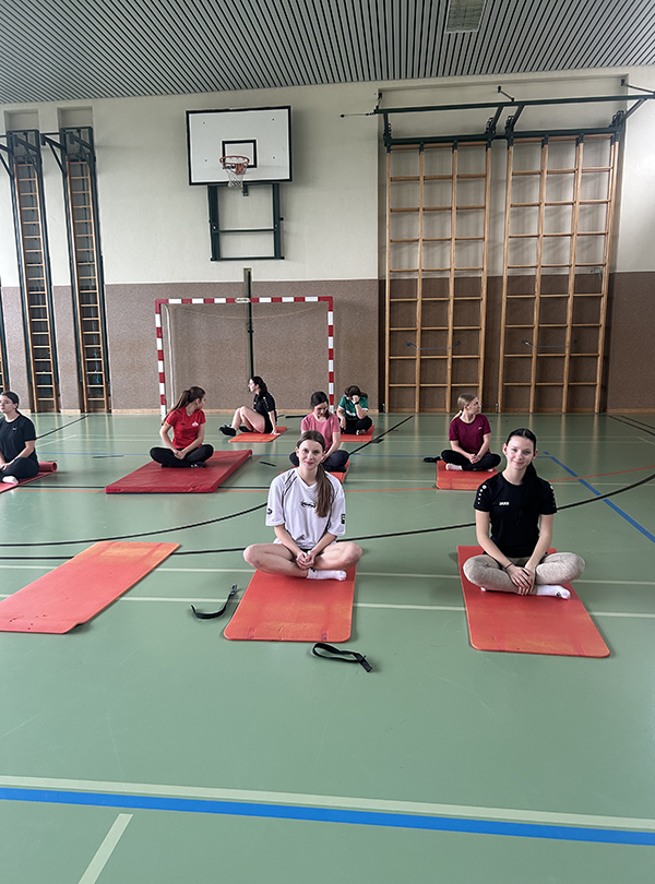 Schülerinnen sitzen auf Yogamatten