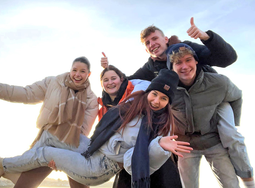 Schüler*innen halten Schülerin hoch, Winterkleidung, draußen