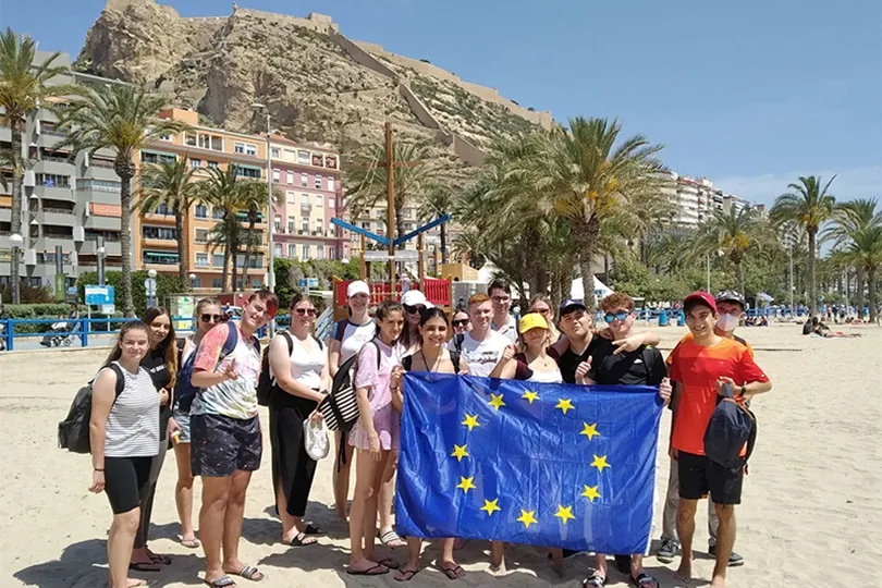 Schülergruppe mit Europafahne am Strand von Valencia