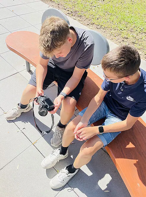 Zwei Schüler sehen sich eine Kompaktkamera an