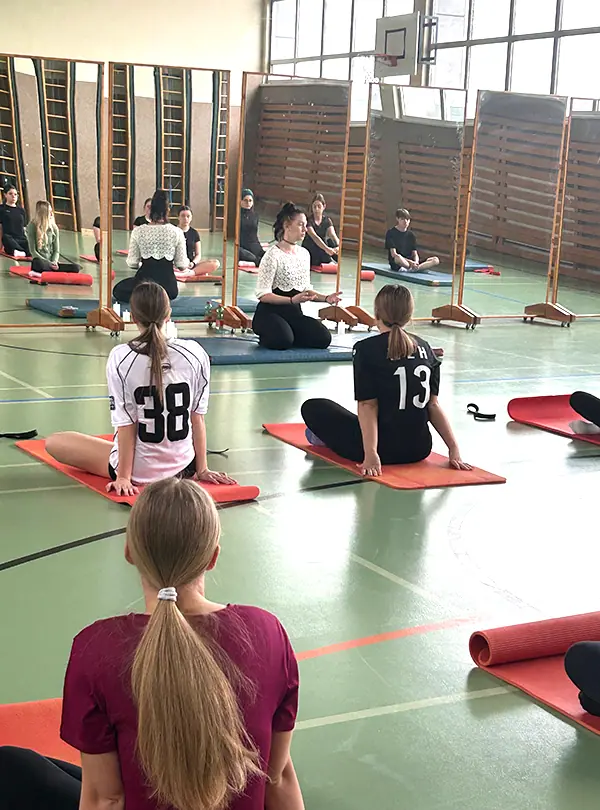 Schülerinnen sitzen auf Yogamatten