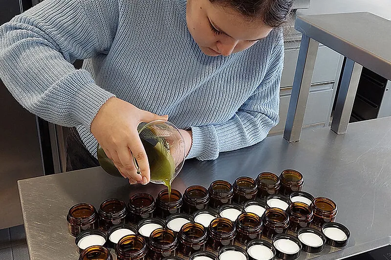 Schülerin füllt selbst hergestellte Kräuterprodukte ab